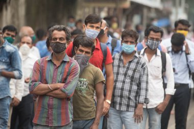 MUMBAI / INDIA - 12 Ekim 2020: Bir Covid-19 koronavirüs salgını sırasında Andheri 'de toplu taşıma otobüsüne binmek için maske takan banliyö sakinleri bekleyin. 