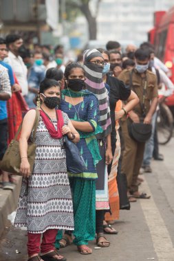 MUMBAI / INDIA - 12 Ekim 2020: Bir Covid-19 koronavirüs salgını sırasında Andheri 'de toplu taşıma otobüsüne binmek için maske takan banliyö sakinleri bekleyin. 