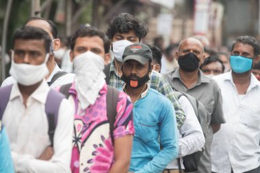 MUMBAI / INDIA - 12 Ekim 2020: Bir Covid-19 koronavirüs salgını sırasında Andheri 'de toplu taşıma otobüsüne binmek için maske takan banliyö sakinleri bekleyin. 
