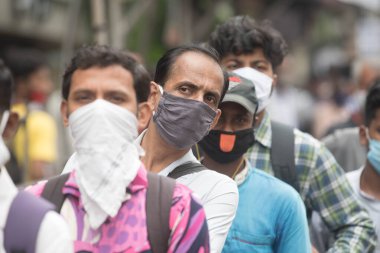 MUMBAI / INDIA - 12 Ekim 2020: Bir Covid-19 koronavirüs salgını sırasında Andheri 'de toplu taşıma otobüsüne binmek için maske takan banliyö sakinleri bekleyin. 