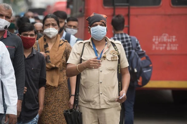 MUMBAI / INDIA - 12 Ekim 2020: Covid-19 Coronavirus salgını sırasında Andheri 'de bir toplu taşıma otobüsüne binmeden önce maske takan kondüktör yolcu için bir bilet 