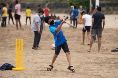 MUMBAI / INDIA - 11 Ekim 2020: Hükümet COVID-19 Coronavirus 'a karşı tedbir olarak tecrit kısıtlamasını gevşettikten sonra Juhu plajında maske takan çocuklar kriket oynuyorlar.