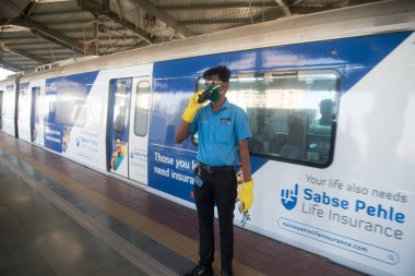 MUMBAI / INDIA - 17 Ekim 2020: Andheri metro istasyonundaki Covid-19 Coronavirus salgını nedeniyle metro şebekesi 6 aydan uzun bir süre kapatıldıktan sonra hizmete devam etmeye hazırlanırken çalışanlar telsizle konuşuyor.