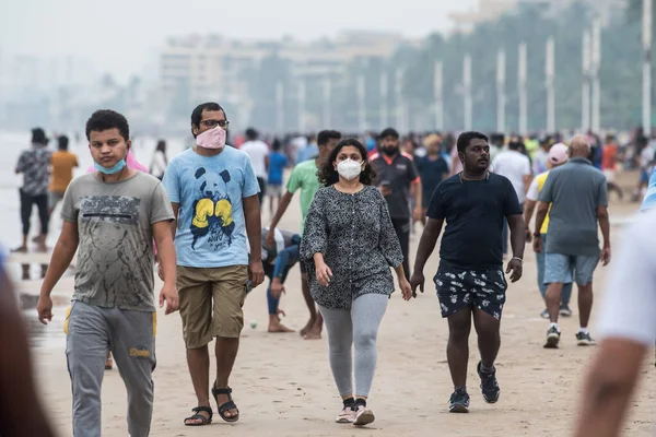 MUMBAI / INDIA - 11 Ekim 2020: Hükümet COVID-19 Coronavirus 'a karşı tedbir olarak tecrit kısıtlamasını gevşettikten sonra maskeli insanlar Juhu plajında yürüyor.