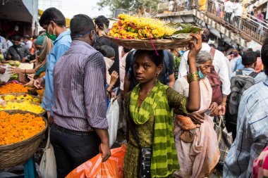 MUMBAI / INDIA - 24 Ekim 2020: Bir kadın Covid-19 Coronavirus salgını sırasında Hindu Dussehra festivali vesilesiyle Dadar pazarında satmak için içi çiçek dolu bir sepet taşıyor.