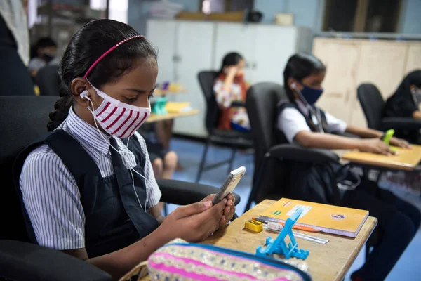 MUMBAI / INDIA - 27 Ekim 2020: Covid-19 Coronavirus salgını sırasında Mumbai 'deki Imamwada' da Online Education Mobile Library 'nin bir parçası olarak ders sırasında cep telefonlarında yüz maskesi takan öğrenciler