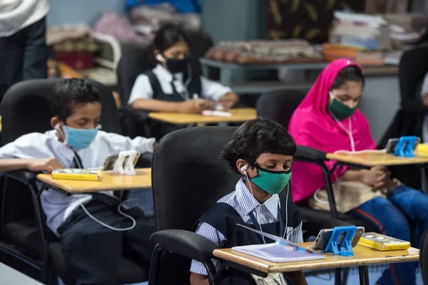 MUMBAI / INDIA - 27 Ekim 2020: Covid-19 Coronavirus salgını sırasında Mumbai 'deki Imamwada' da Online Education Mobile Library 'nin bir parçası olarak ders sırasında cep telefonlarında yüz maskesi takan öğrenciler
