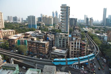 MUMBAI / INDIA - 27 Ekim 2020: Covid-19 Coronavirus salgını nedeniyle tek raylı sistem kapandıktan sonra hizmetlerini sürdürdükten sonra arka planda yerleşim ve ticari tomurcuklanan bir köprünün yanından geçen tek raylı sistem.