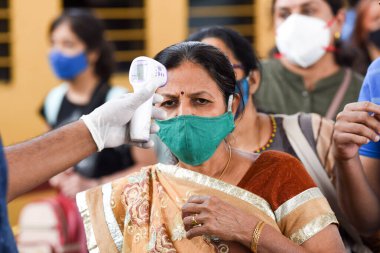 MUMBAI-INDIA - 17 Ocak 2021: Bir sağlık çalışanı COVID-19 test sürüşü sırasında Dadar istasyonundaki bir yolcunun vücut sıcaklığını kontrol eder.