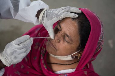 MUMBAI-INDIA - 18 Ocak 2021: Sağlık çalışanları, Dadar istasyonunda COVID-19 testi için gelen bir yolcunun burnundan örnek alıyor.