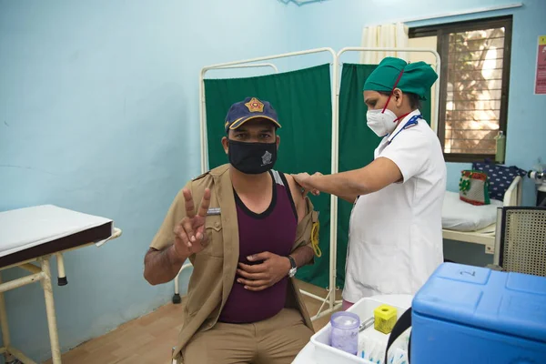 MUMBAI-INDIA - February 9, 2021: A medical staff inoculates a police personnel with a Covid-19 coronavirus vaccine at a vaccination center, Rajawadi Hospital.