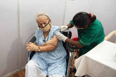 MUMBAI-INDIA - March 1, 2021: A medical staff inoculates a man with a Covid-19 coronavirus vaccine at the  BKC vaccination center, as the country begins a vaccination programme for senior people.