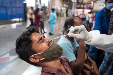 MUMBAI - INDIA - April 2, 2021: Health workers collects a swab sample from a passenger for a RT- PCR test for the Covid-19 coronavirus at Chhatrapati Shivaji Maharaj terminus.