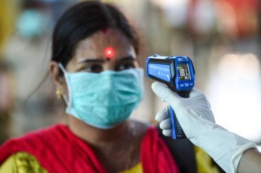 MUMBAI-INDIA - 22 Mart 2020: COVID-19 Coronavirus 'a karşı önleyici bir önlem olarak ülke çapındaki tecrit sırasında Lokmanya Tilak terminalindeki yolcuların vücut sıcaklığını izleyen sağlık çalışanı.