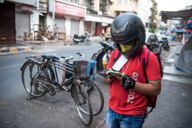 MUMBAI / INDIA - 18 Nisan 2020: Zomato dağıtım ajanı, COVID-19 Coronavirus 'a karşı önleyici bir önlem olarak ülke çapındaki tecrit sırasında Fort' taki düzen detaylarını kontrol eder.