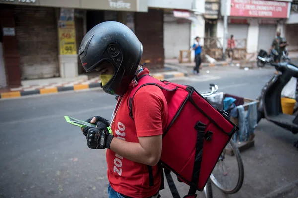 MUMBAI / INDIA - 18 Nisan 2020: Zomato dağıtım ajanı, COVID-19 Coronavirus 'a karşı önleyici bir önlem olarak ülke çapındaki tecrit sırasında Fort' taki düzen detaylarını kontrol eder.