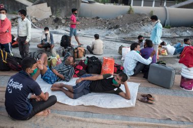 MUMBAI / INDIA - 9 Mayıs 2020: Göçmen işçiler, COVID-19 Coronavirus 'un yayılması ile savaşmak için ülke çapındaki tecrit sırasında otoyolda dinleniyorlar..