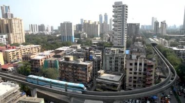 MUMBAI-INDIA - 27 Ekim 2020: Monoray ağı Covid-19 Coronavirus salgını nedeniyle kapandıktan sonra hizmetlerini sürdürdükten sonra arka planda tomurcuklanan bir köprünün yanından geçen tek raylı tren..
