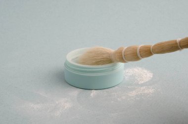 Mavi arka planda yakın plan kozmetik fırçası ve pudra