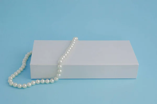 Eine Schöne Perlenkette Auf Einer Weißen Schachtel Auf Blauem Hintergrund — Stockfoto
