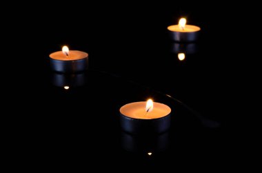 Yansımalı siyah arkaplanda yanan mum