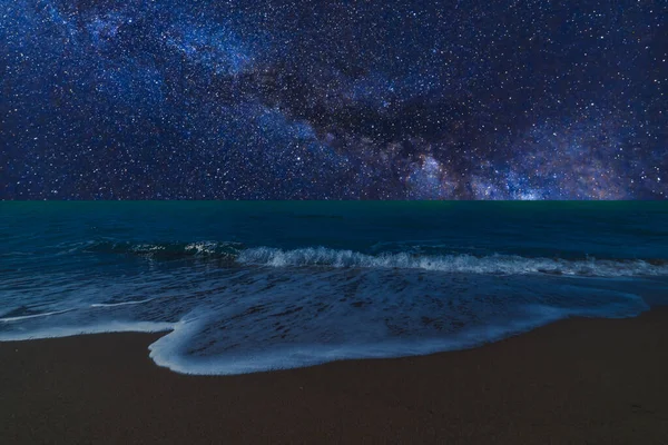 Gece deniz manzarası, parlak gökyüzü, samanyolu, dalgalı deniz ve kum.