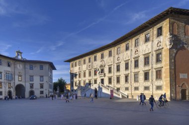 Piazza dei Cavalieri, Pisa. Palazzo della Carovana ve Palazzo dell 'Orologio tarafından çerçevelenmiş, açık mavi gökyüzünün altında, hayat dolu