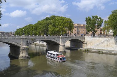 Giuseppe Mazzini Köprüsü, Tiber Nehri boyunca bir turist teknesiyle geçmektedir.