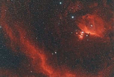 Atbaşı Bulutsusu ve Ateş Bulutsusu 'nun (Orion) geniş, parıldayan Sh2 emisyon bölgelerine karşı geniş bir görüş alanı. Koyu kırmızı renk hidrojen gaz bulutlarını ve karanlık kozmik tozu vurgular.