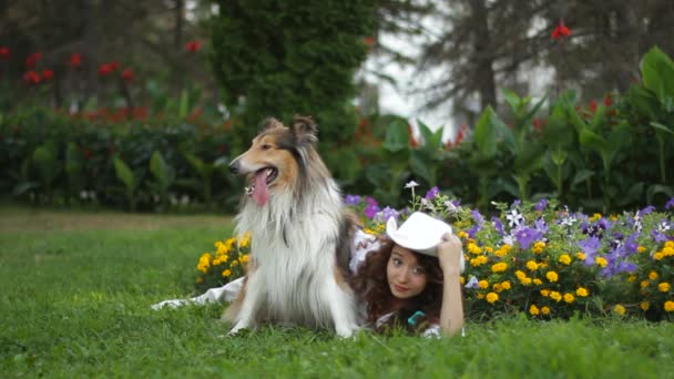 Fille avec chien reposant dans une clairière dans le parc — Video