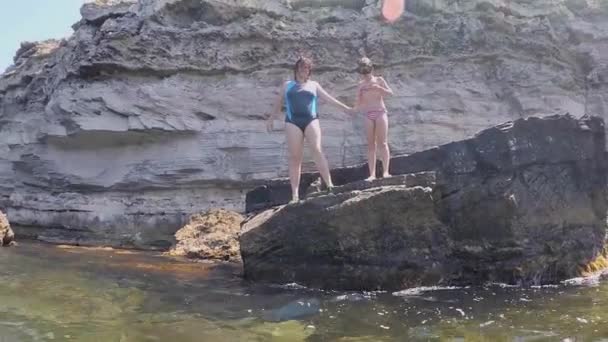 Mutter und Tochter springen von einer Klippe ins Wasser. Videoaufnahme auf dem Torbogen — Stockvideo