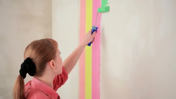 Девушка рисует стену с цветными полосками — стоковое видео