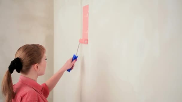 Una guapa rubia pinta la pared de rosa . — Vídeos de Stock