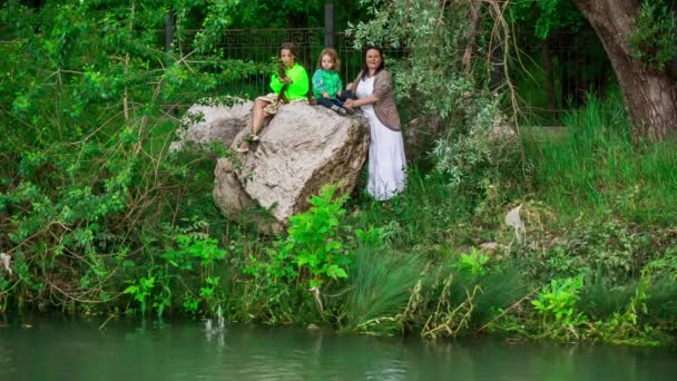 母と 2 人の子供は池に石を投げる — ストック動画