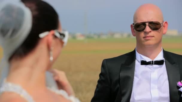 Feliz novio y novia en gafas de sol posando en la naturaleza — Vídeos de Stock