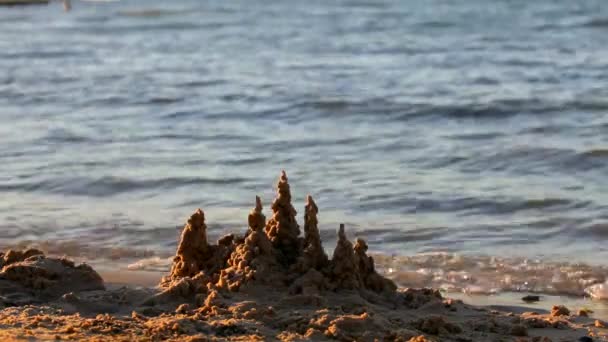 一座小的沙堡海滩上与波背景上. — 图库视频影像