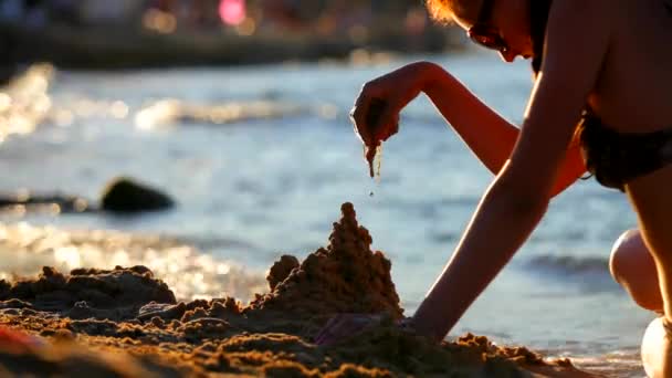 Dziewczyna nad morzem buduje zamek z piasku — Wideo stockowe
