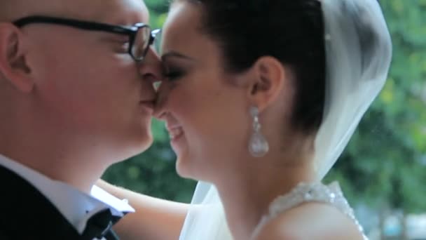 Les jeunes mariés heureux s'embrassent pendant la pluie 