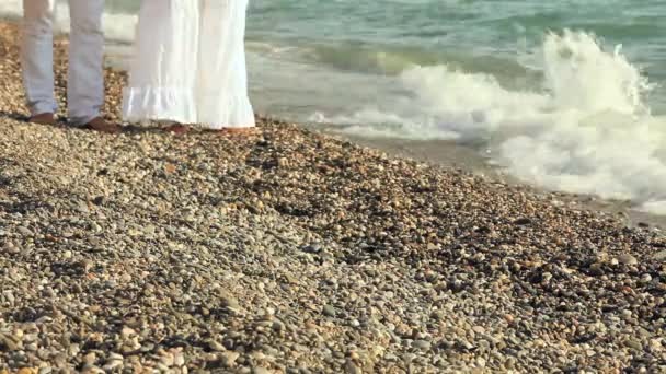 Heterosexuelles Paar in weißen Kleidern spaziert am Meer entlang — Stockvideo