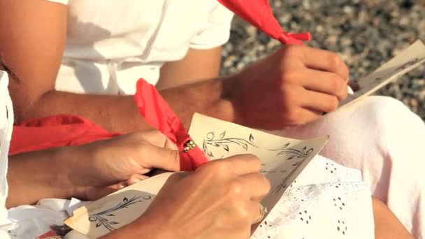 Ung Man och kvinna i kärlek skriva romantiska önskningar sitter på stranden — Stockvideo