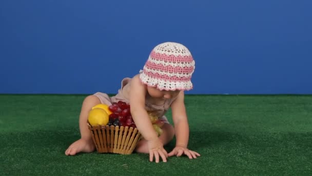 Criança ao lado de uma cesta de frutas suculentas — Vídeo de Stock