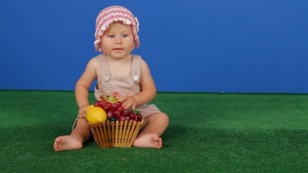 Niña sosteniendo uvas en un fondo azul — Vídeos de Stock