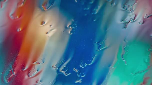Gotas de agua corriendo sobre vidrio durante la lluvia con fondo colorido — Vídeo de stock