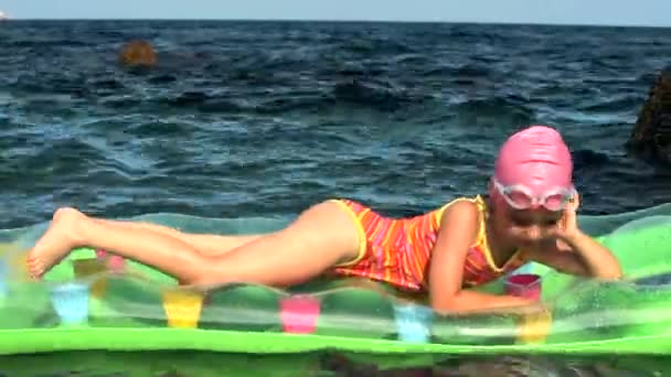 Маленька дівчинка на матраці в морі — стокове відео