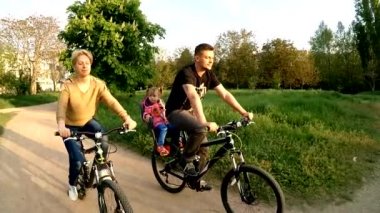 Yeşil park bisiklet sürme çocuk ile genç aile