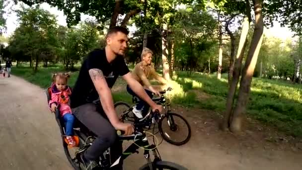 Счастливая семья из трех велосипедов в зеленом парке — стоковое видео