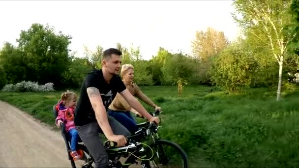 Junge Familie radelt im grünen Park — Stockvideo