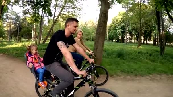 Família feliz de três bicicletas de equitação no parque verde — Vídeo de Stock