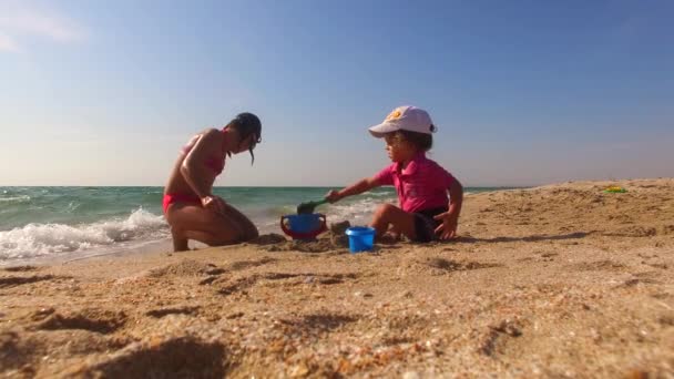 Gyerekek játszanak homokkal a strandon — Stock videók