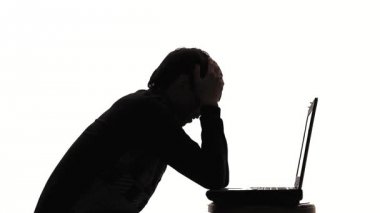 Laptop çalışan genç adam silüeti,